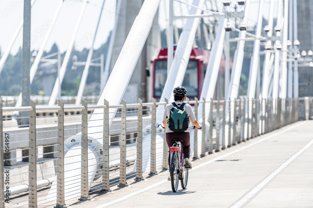 Woman with a backpack rides a bicycle on a bike path at Tilikum Crossing Bridge