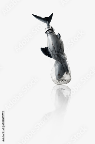 Creative concept background by photo of shark ( toy model) stuck in transparent blue plastic bottle ,with copy space. photo