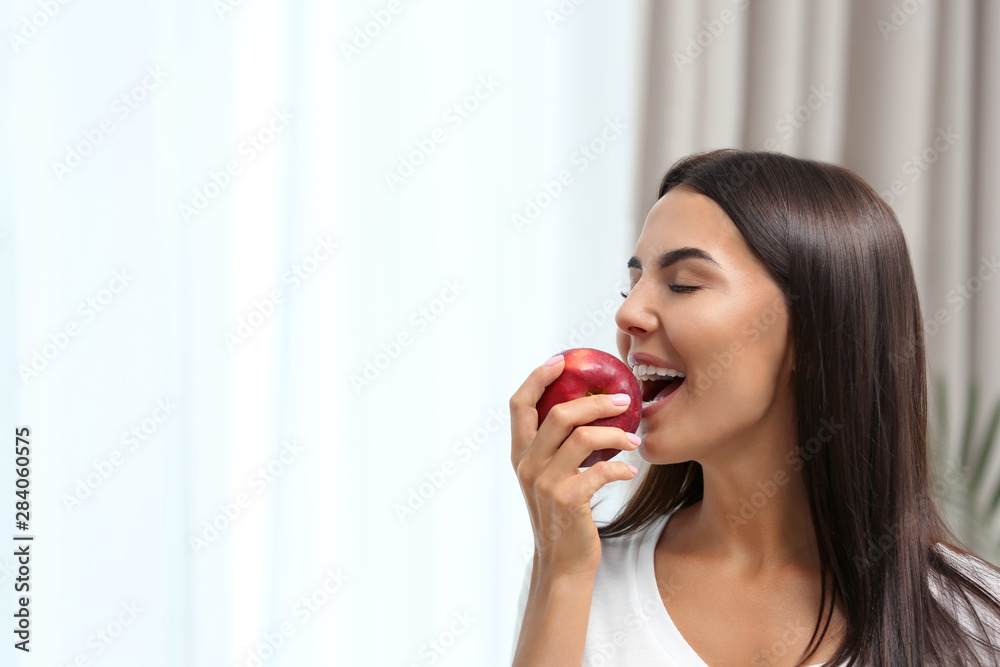 Woman eating red apple indoors. Space for text Woman eating red apple indoors. Space for text