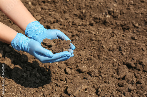 Woman holding pile of soil outdoors, closeup. Space for text