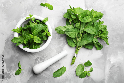 Fresh mint with mortar and pestle on grey marble table, flat lay