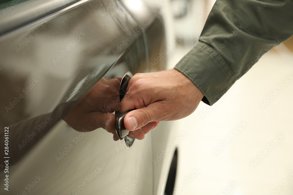 Young man opening car door in modern auto dealership, closeup Young man opening car door in modern auto dealership, closeup