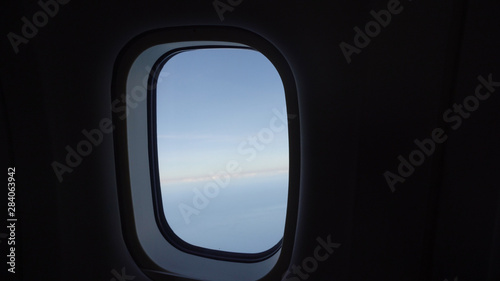 Clouds in the aircraft's porthole. Blue sky view from airplane window.