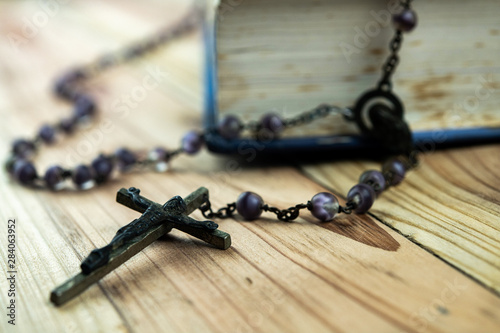 Fotografie Closeup main focus crucifix with Catholic rosary beads and Bible on wooden background