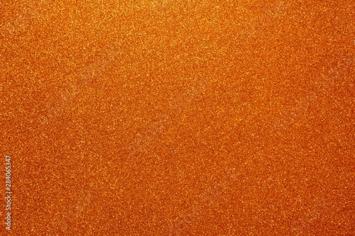 Orange glitter. Abstract shiny background. Design paper texture for decoration and design of Christmas, New Year or other holiday pictures. Beautiful packaging material.