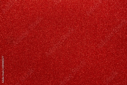 Red glitters abstract shiny background. Scarlet design paper texture for decoration and design of Christmas, New Year or other holiday pictures. Beautiful packaging material.