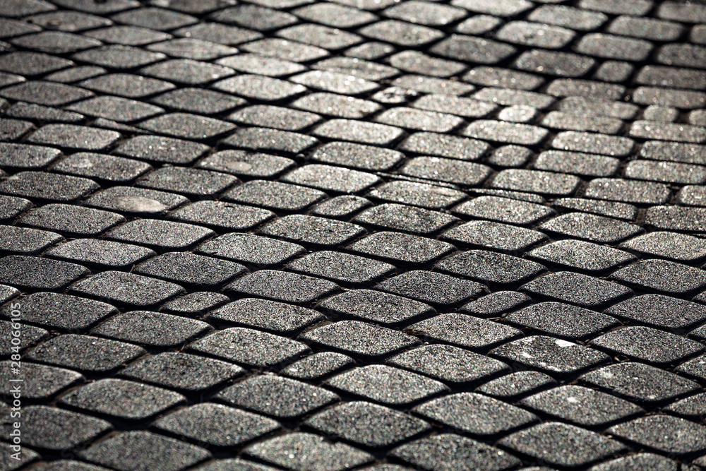 Cobble paving stone sidewalk of old town in evening sunlight. Abstract background.