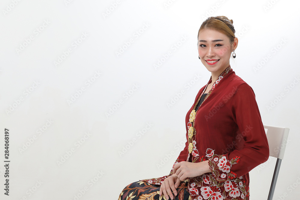 Asian woman traditional red maroon kebaya sharong on white background sitting pose chair sit