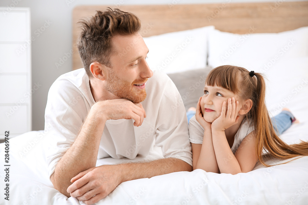 Portrait of happy father and his little daughter lying on bed Portrait of happy father and his little daughter lying on bed