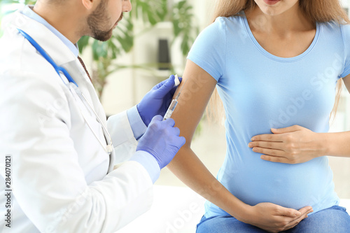 Doctor vaccinating pregnant...