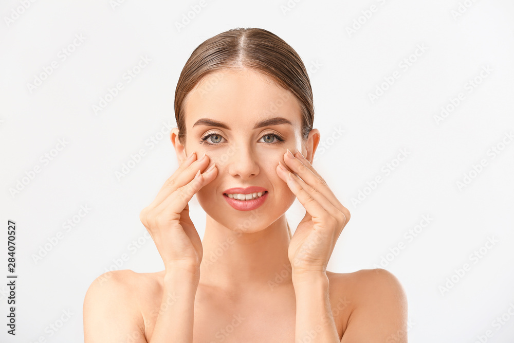 Beautiful woman massaging her face against white background Beautiful woman massaging her face against white background