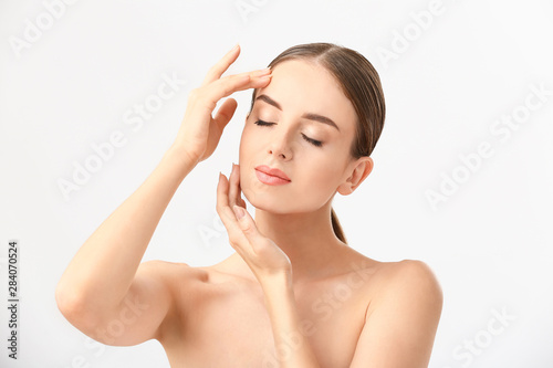 Beautiful woman massaging her face against white background