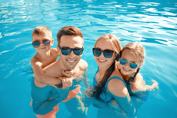 Happy family in swimming pool on summer day