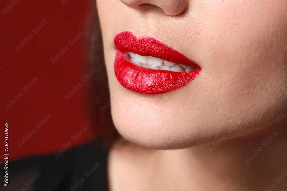 Obraz premium Beautiful young woman with bright lipstick on color background, closeup