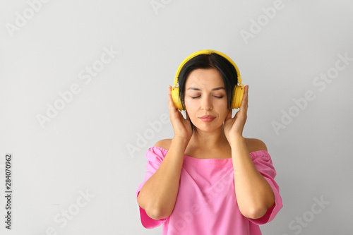 Portrait of beautiful woman listening to music on grey background