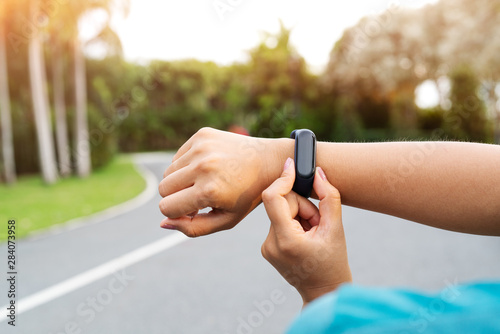 fitness woman runner setting up smart watch before running. Outdoor exercise activities