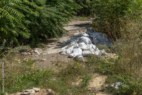 Plastic bottles bags and other household garbage were thrown along road. Garbage on side of road. Environmental pollution concept. Spontaneous illegal dumping of unnecessary household waste along road