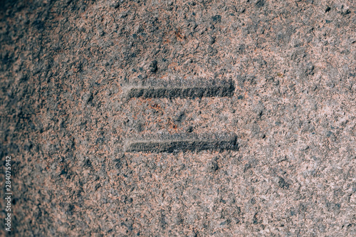 An equal sign carved on the stone. Mathematical sign on granite. Stone engraving photo
