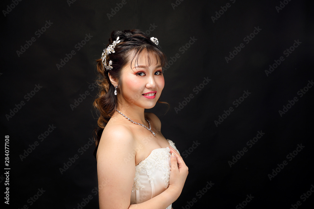 Young Asian woman in white dress hair crown on black background