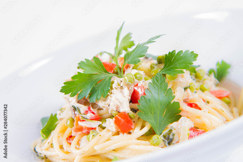 Spaghetti with cream sauce with smoked mackerel, peas ,bell pepper and some parsley on a white plate on a white background Spaghetti with cream sauce with smoked mackerel, peas ,bell pepper and some parsley on a white plate on a white background