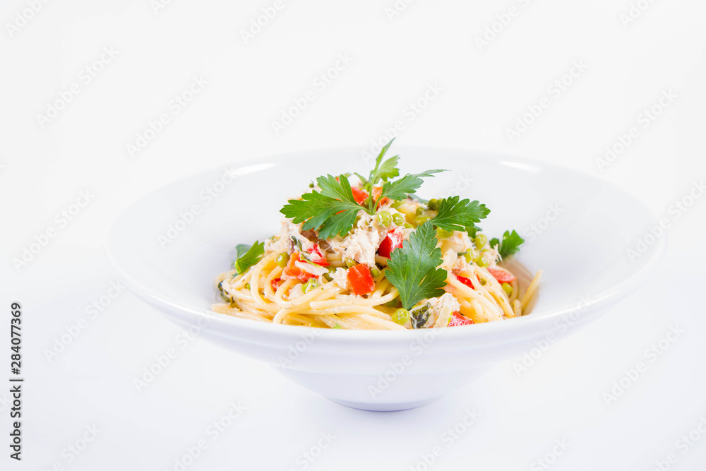 Spaghetti with cream sauce with smoked mackerel, peas ,bell pepper and some parsley on a white plate on a white background Spaghetti with cream sauce with smoked mackerel, peas ,bell pepper and some parsley on a white plate on a white background