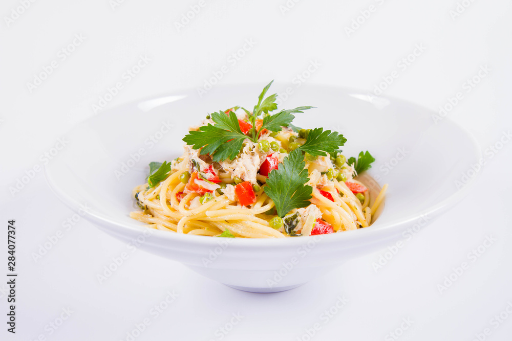 Spaghetti with cream sauce with smoked mackerel, peas ,bell pepper and some parsley on a white plate on a white background Spaghetti with cream sauce with smoked mackerel, peas ,bell pepper and some parsley on a white plate on a white background