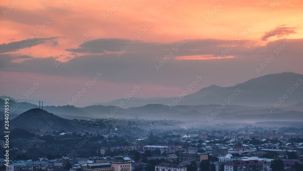 Panoramic view of the city of Akhaltsikhe in Georgia at dawn in a blue haze against the background of mountains