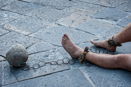 Prisioner with ball and chain in the court of the prison. Close up. Concept of inhuman and degrading detention conditions. photo