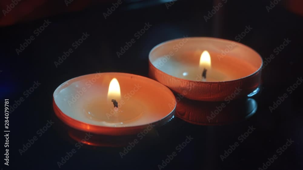 Two small candles floating in the water in the darkness illuminated with warm tones, close up Two small candles floating in the water in the darkness illuminated with warm tones, close up