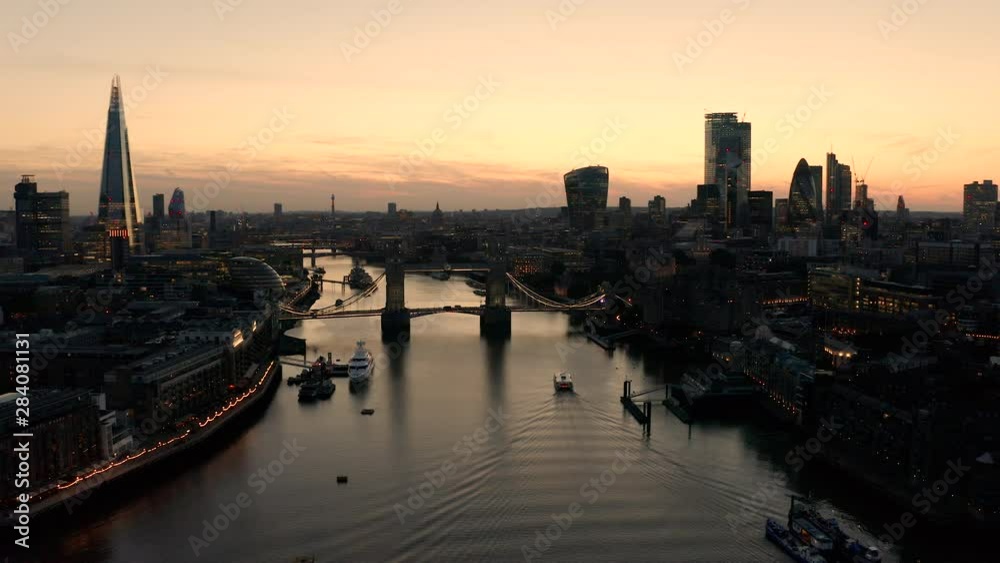 Aerial view of London, River Thames and Tower Bridge just after the sun has set and the sky is lit. A pleasure cruiser heads towards the bridge. Aerial view of London, River Thames and Tower Bridge just after the sun has set and the sky is lit. A pleasure cruiser heads towards the bridge.