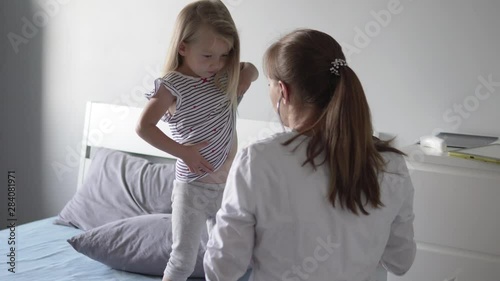 Doctor listens to a little girl in a hospital with a stethoscope.
