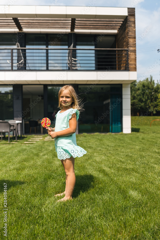 Fototapeta premium Cute girl with lollipop on the grass stock photo