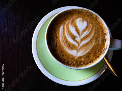 Cup of cappuccino with latte art wooden background.