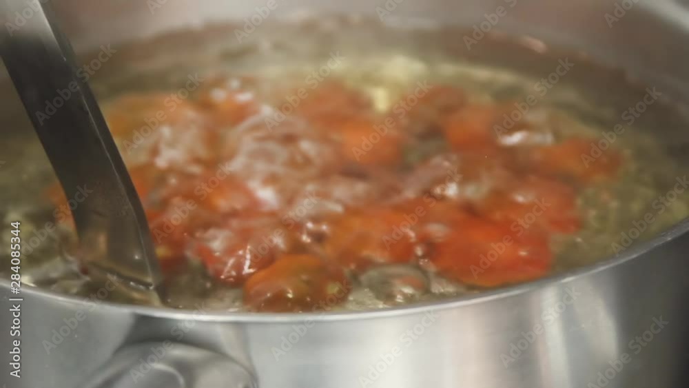 Cherry tomatoes are cooking in a saucepan. Tomatoes are cooking in the kitchen of the restaurant. Red cherry tomatoes are cooking. Hands dipping cherry tomatoes in water. Close up food video Cherry tomatoes are cooking in a saucepan. Tomatoes are cooking in the kitchen of the restaurant. Red cherry tomatoes are cooking. Hands dipping cherry tomatoes in water. Close up food video