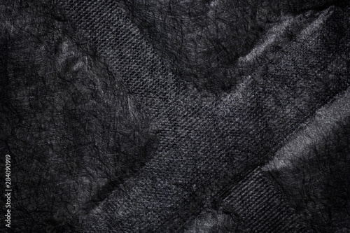 Black fabric canvas silk texture background. Abstract closeup detail of textile material wallpaper. X cross shape emboss