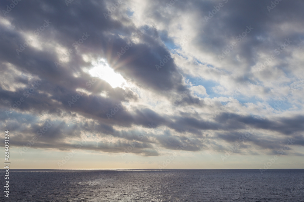Obraz premium Sun filtering through the clouds over the sea