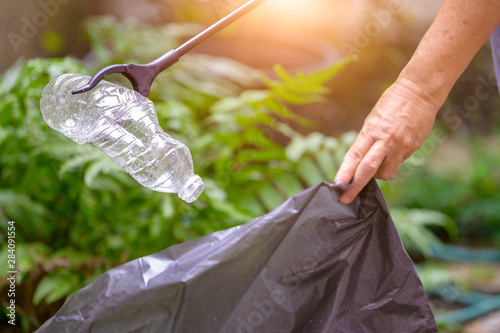 Canvas-taulu Closeup of hand and waste grabber picking up drinking plastic bottle waste into bag