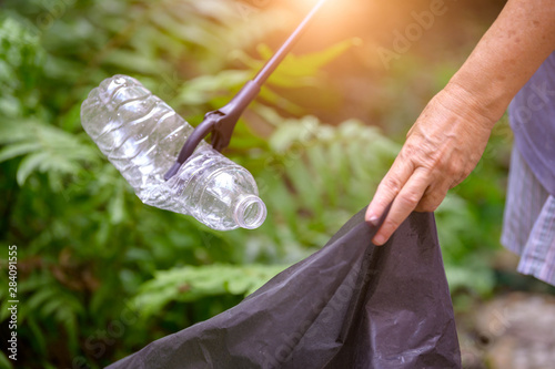 Принти на полотні Closeup of hand and waste grabber picking up drinking plastic bottle waste into bag