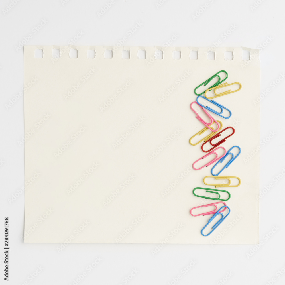 Bright multicolored paper clips on paper against white background Bright multicolored paper clips on paper against white background