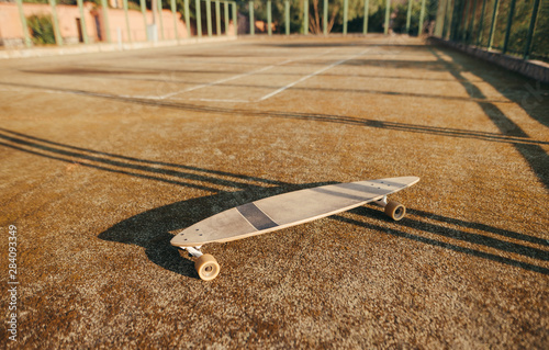 Background. Photo of a longboard on the playground. Blackboard on old tennis court. Street culture.Longboarding concept. Copy space photo