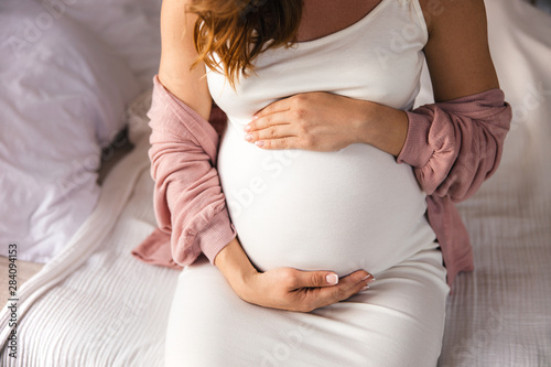 Young pregnant woman gently holding her belly