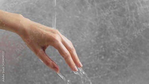 Water flows through the woman's hand on grey background. Time as water flows through the fingers. Hand close-up. photo