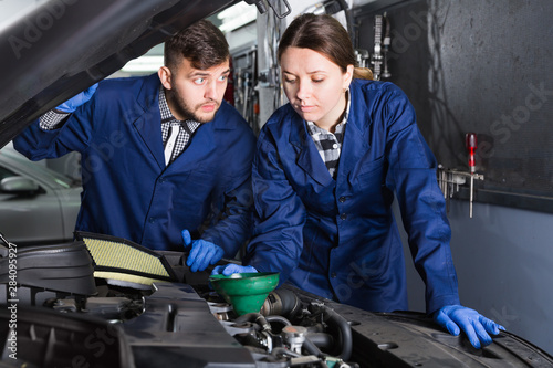 Female master with foreman are replacing the oil in car