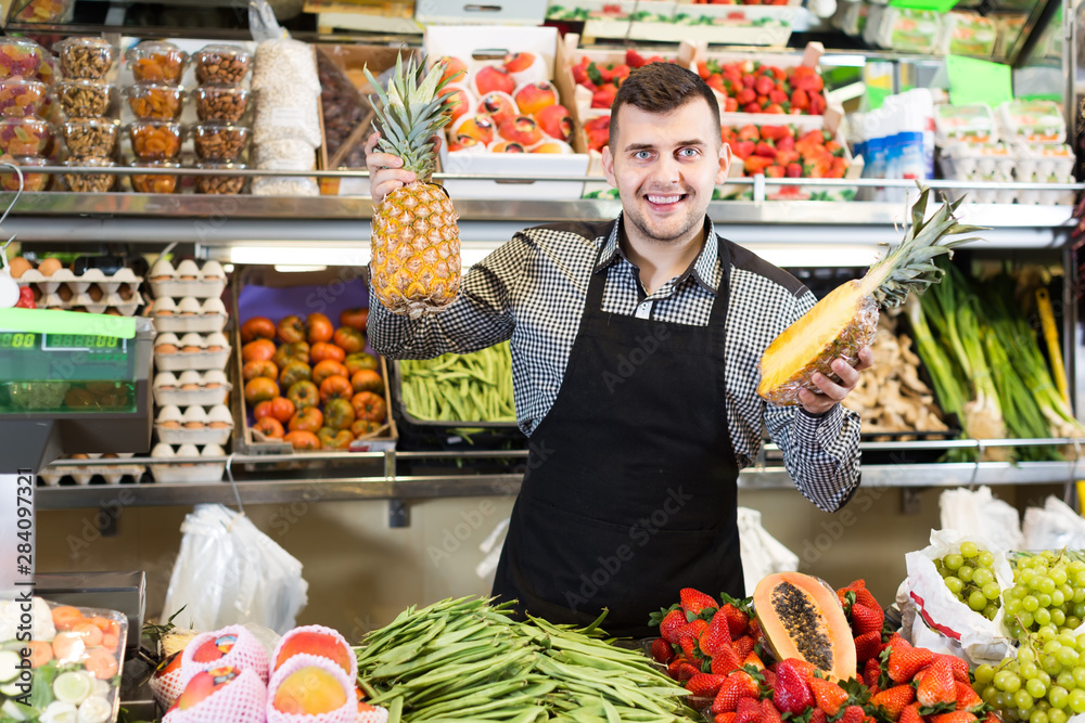 Smiling man seller showing assortment of grocery shop