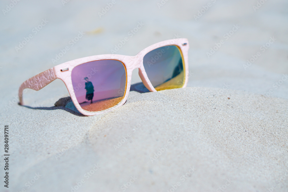 Young woman reflect in pink sunglasses on the beach, summer concepts