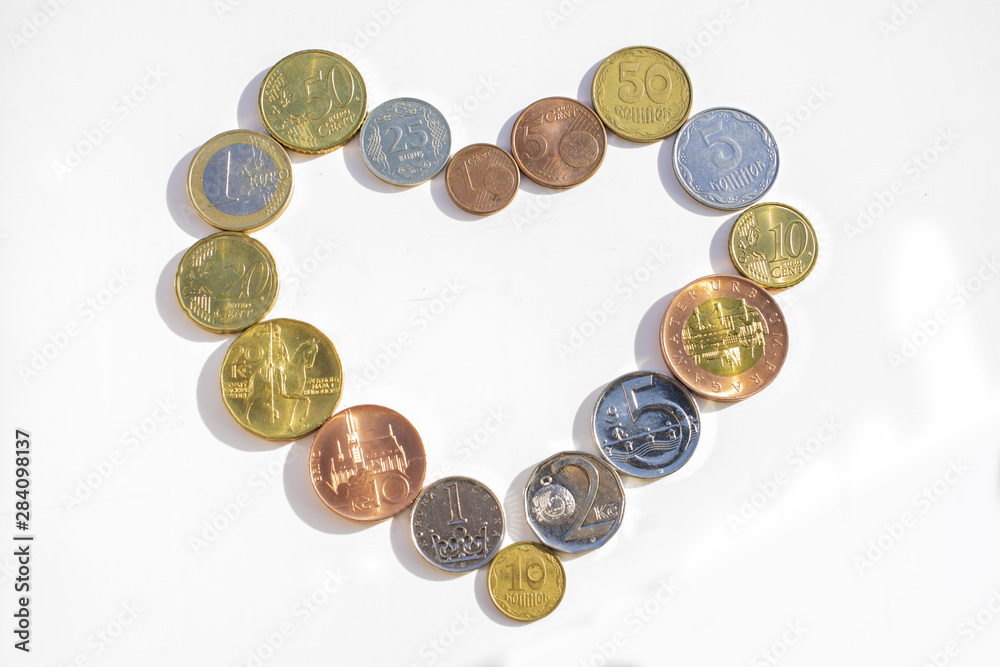 Coins of different countries laid out in the shape of a heart on a white background. Coins of different countries laid out in the shape of a heart on a white background.