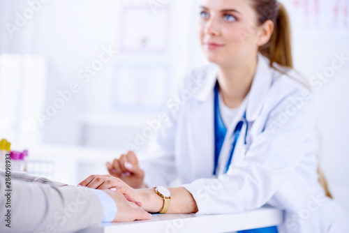 The doctor holds the patient s hand in the office. Young specialist reassures patient