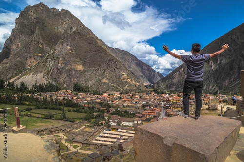 Tourist observing the city with a panoramic view in Ollantaytambo is a town in the Sacred Valley of Peru, which lies south on the Urubamba River and is surrounded by snow-capped mountains.