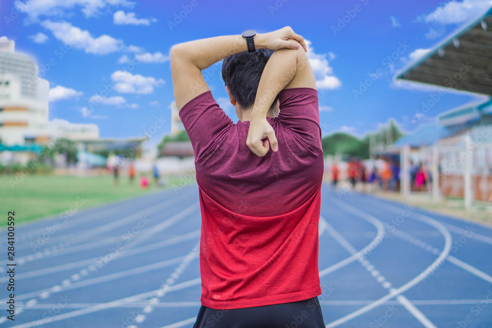 Young man stretching his arms before exercising and running. Young man warming up outdoors. Sport and exercise concept.