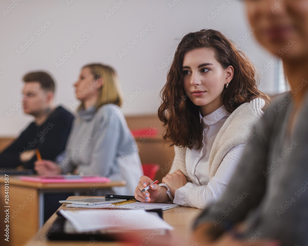 Beautiful girl taking notes in multinational group of students in an auditorium Beautiful girl taking notes in multinational group of students in an auditorium